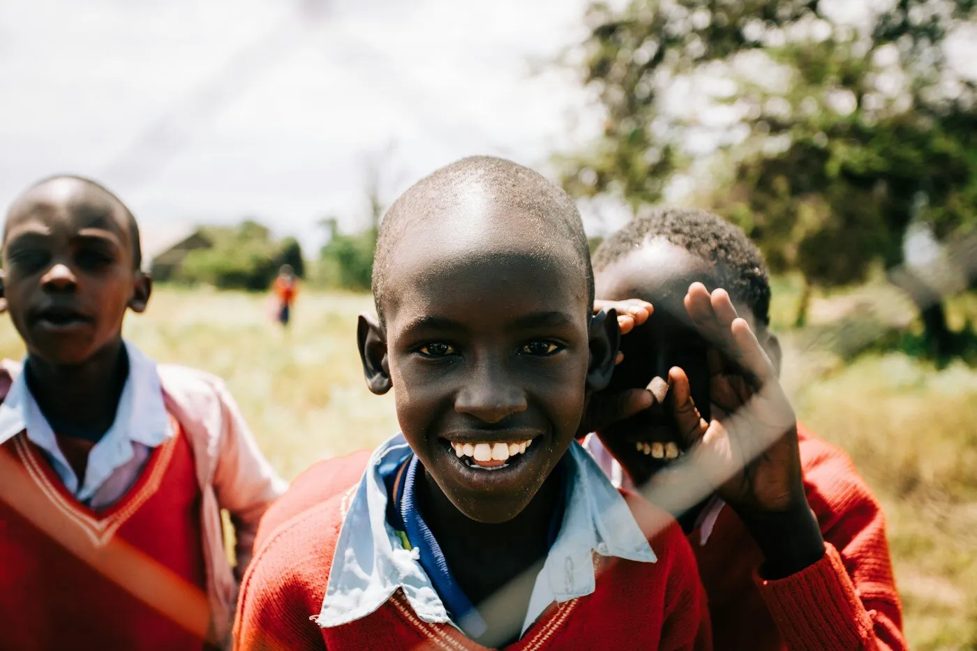 Three African boys smiling together outside a school in Kenya