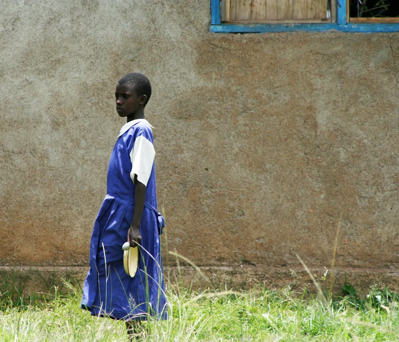 African boy in school uniform standing on green grass in Kenya