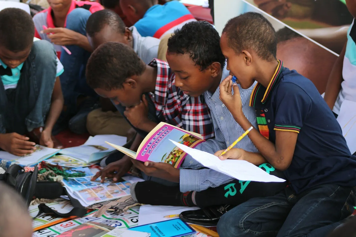 African boy in blue shirt reading a book
