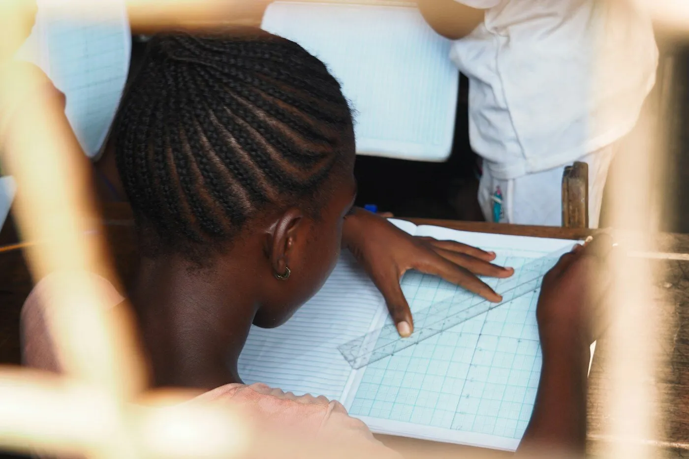 African student carefully drawing lines with a ruler in class