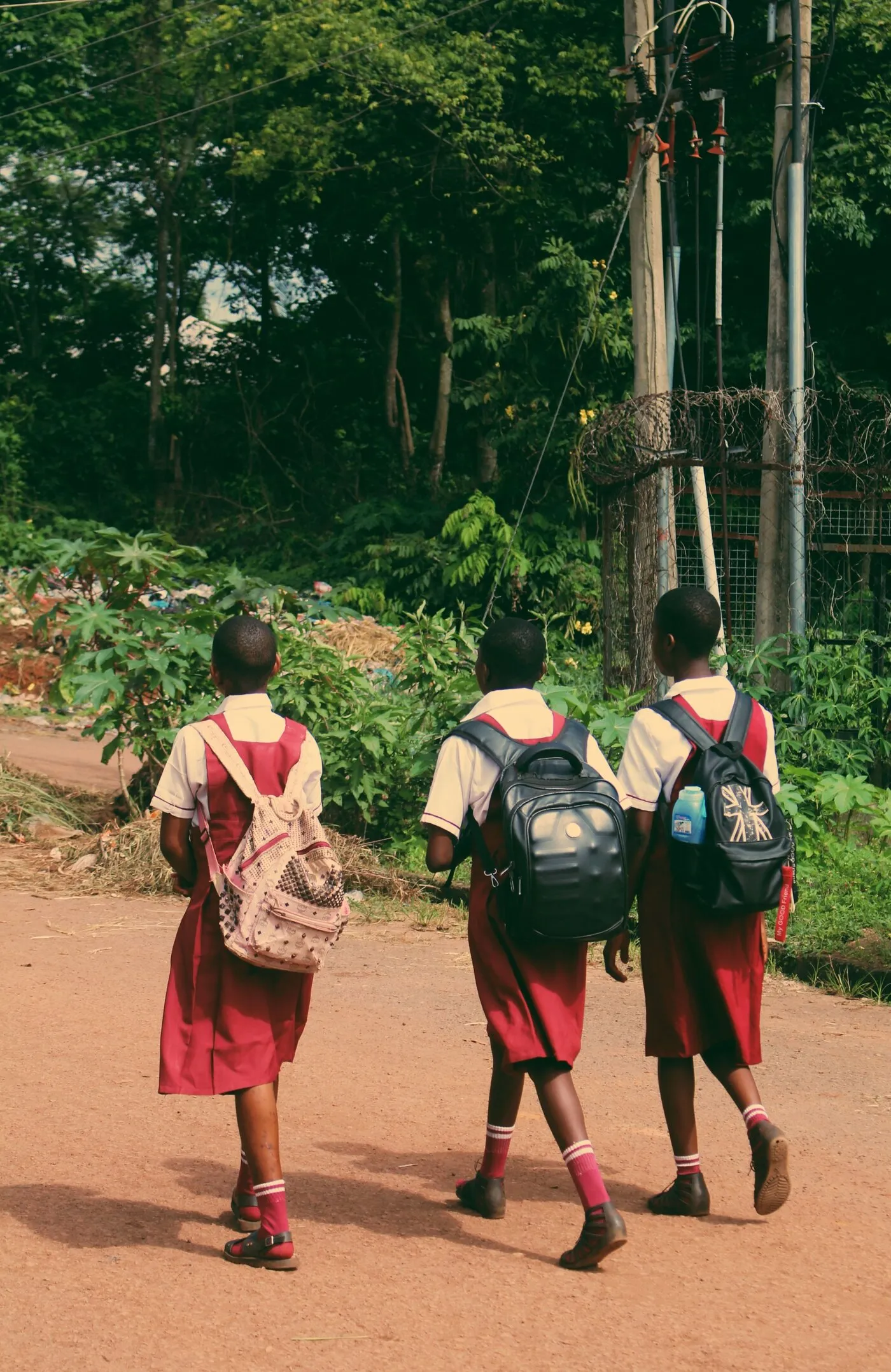 Three African students in red school uniforms walking in Nigeria