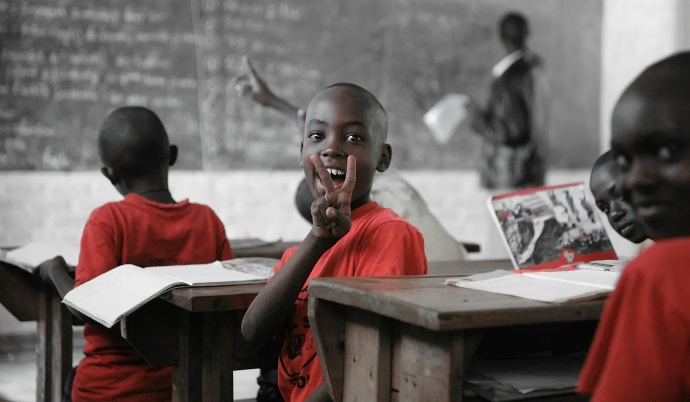 African boy in red shirt sitting on a chair in a classroom